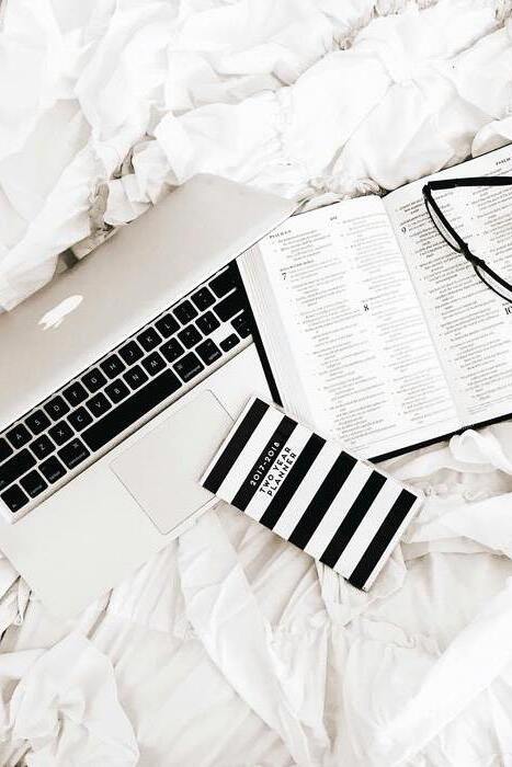 Un ordinateur, un livre, des lunettes et un carnet sur un lit