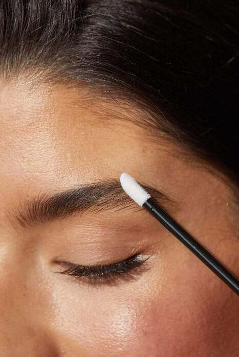 Une femme passe un pinceau sur son sourcil